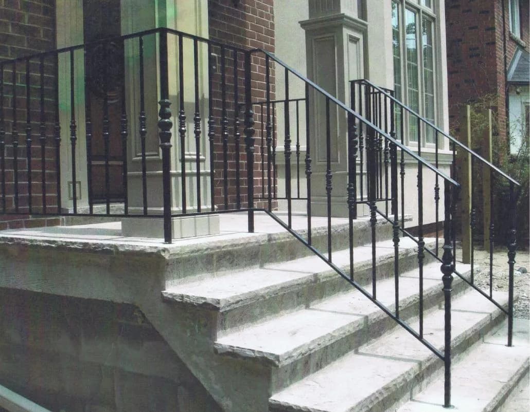 Black iron railing with turned decorative balusters on a stone porch and front steps
